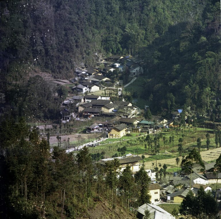 Aerial view of a picturesque village in Hà Giang, Vietnam, surrounded by lush greenery and mountains.