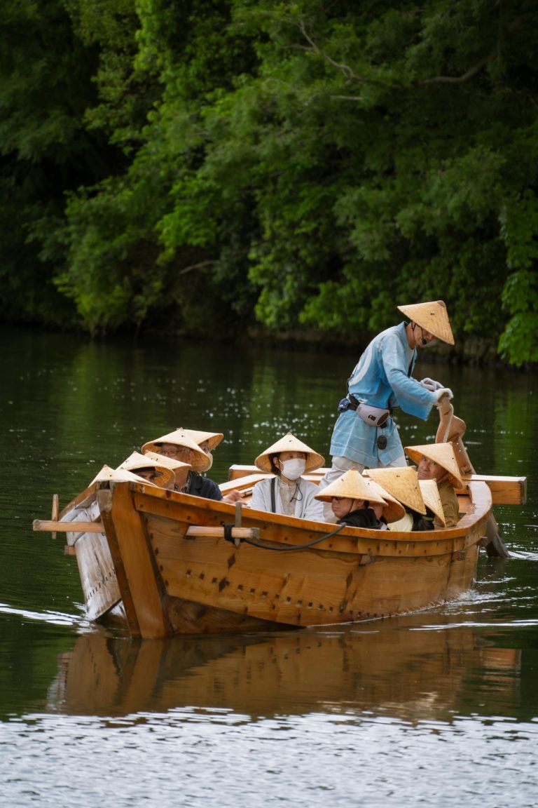 Scenic boat ride with people in traditional hats on a river in Himeji, Hyogo, Japan.
